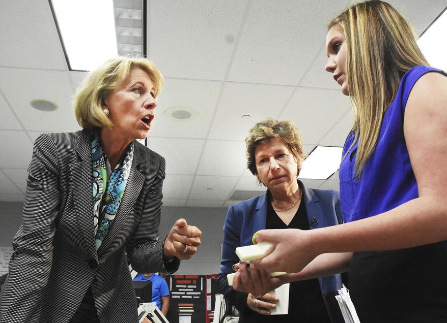 American Federation of Teachers President Randi Weingarten, center, listens as Education Secretary Betsy DeVos, left, talks to Van Wert High School freshman Alaina Arney about a patent she has applied for on a protective unit for a flush valve, during a visit to the Van Wert Robotics Club at Van Wert High School, Thursday, April 20, 2017, in Van Wert, Ohio. (Cathie Rowand/The Journal-Gazette via AP)