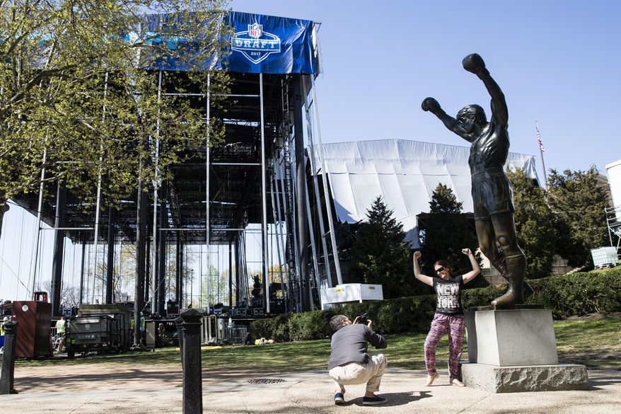 Tourist make photos with the Rocky statue as workmen construct the stage for the upcoming 2017 NFL football draft on the steps of the Philadelphia Museum of Art in Philadelphia, Tuesday, April 18, 2017. When the NFL chose Philadelphia to host the 2017 draft, they insisted on holding the three-day event at the Art Museum in front of the iconic Rocky steps. Mayor Jim Kenney and city officials made it happen so construction crews are putting together a 3,000-seat theater for an extravaganza that's expected to draw about 200,000 people to the venue. (AP Photo/Matt Rourke)
