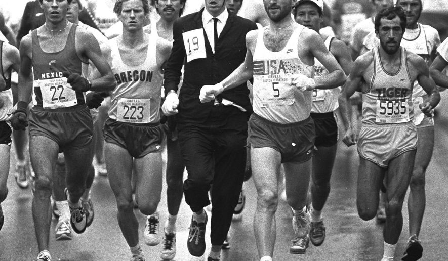 FILE - In this Monday, April 17, 1984, file photo, an unidentified man wearing a business suit and black hat, runs with the Boston Marathon pack along the course from Hopkinton to Boston, flanked by D.J. Harding (223) of Oregon, and Tom Fleming (5) of New Jersey. Fleming, a two-time winner of the New York City Marathon, died Wednesday, April 19, 2017, while coaching his New Jersey middle school team at a meet, in Verona, N.J. (AP Photo/File)