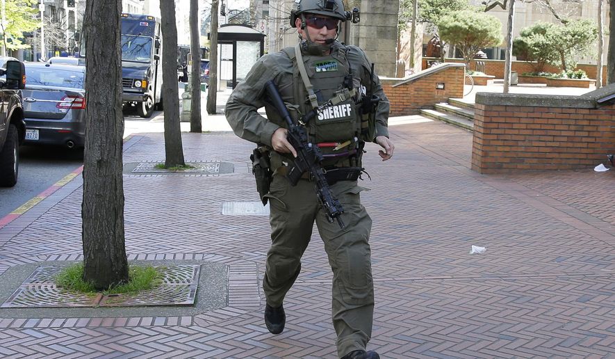 A King County Sheriff's Deputy carries a gun as he runs near the scene of a shooting involving several police officers in downtown Seattle, Thursday, April 20, 2017. (AP Photo/Ted S. Warren)