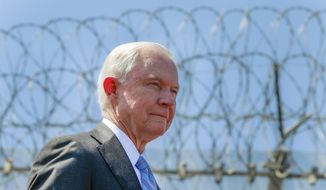 With razor wire across the top of the secondary border fence behind him, United States Attorney General Jeff Sessions stands during a news conference at the U.S.-Mexican border next to the Brown Field Border Patrol Station in San Diego on Friday, April 21, 2017. (Hayne Palmour IV/The San Diego Union-Tribune via AP) ** FILE **