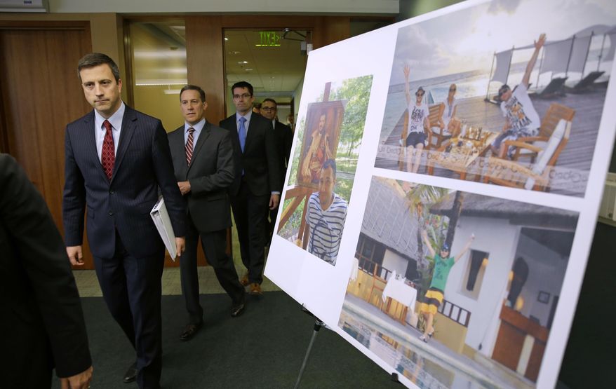 Trevor McFadden, left, acting principal deputy assistant attorney general, and other officials walk past photos of Russian hacker Roman Seleznev as they arrive to talk to reporters, Friday, April 21, 2017, in Seattle, following the federal court sentencing of Seleznev to 27 years in prison after he was convicted of hacking into U.S. businesses to steal credit card data. (AP Photo/Ted S. Warren)