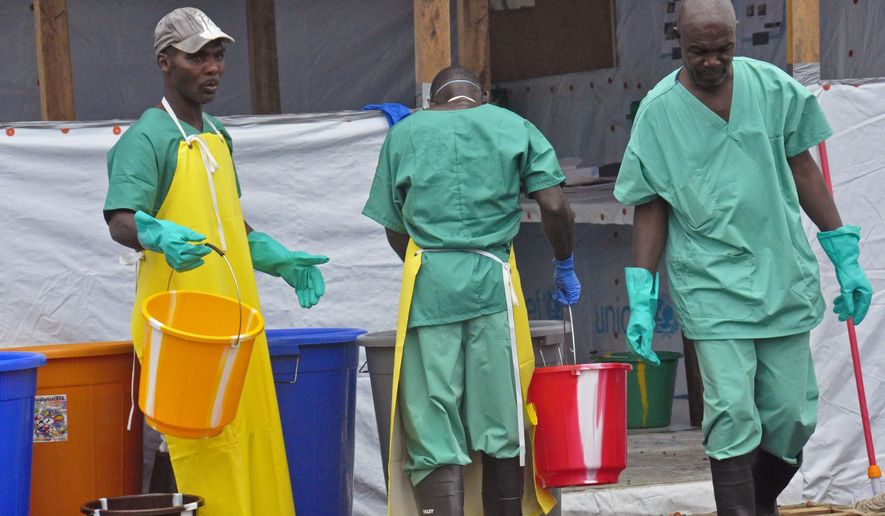 In this Monday, Aug. 18, 2014, file photo, Health workers with buckets, as part of their Ebola virus prevention protective gear, at an Ebola treatment center in Monrovia, Liberia.  The trauma of the world’s deadliest Ebola outbreak, which killed more than 11,300, has left many survivors fighting a mental health battle to focus on the present, after witnessing drawn-out deaths and whole communities torn apart. (AP Photo/Abbas Dulleh, File)