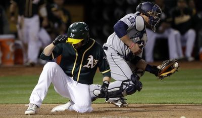 Oakland Athletics' Jed Lowrie scores past Seattle Mariners catcher Carlos Ruiz on a sacrifice fly by Stephen Vogt during the sixth inning a baseball game Friday, April 21, 2017, in Oakland, Calif. (AP Photo/Marcio Jose Sanchez)