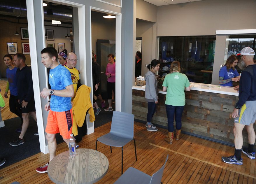 In this Thursday, April 20, 2017 photo, a running group gets ready to leave from the lobby of SingleSpeed Brewing Co. in the former Hostess Wonder Bread building in Waterloo, Iowa. A once crumbling bakery in Waterloo that for decades produced Hostess Wonder Bread is now opening as a brewery, restaurant and distribution center. (Matthew Putney/The Courier via AP)