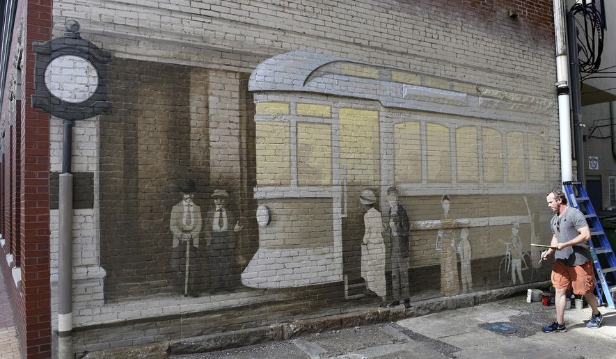 ADVANCE FOR USE MONDAY, APRIL 24 - In this April 14, 2017 photo, artist Jesse Corliss works on a mural of a streetcar scene on a wall in the alley off Quarrier Street between Capitol and Hale Streets in Charleston, W.Va. He said working on the jagged lines and imperfect surface of the brick wall has been a unique challenge. (Chris Dorst/Charleston Gazette-Mail via AP)