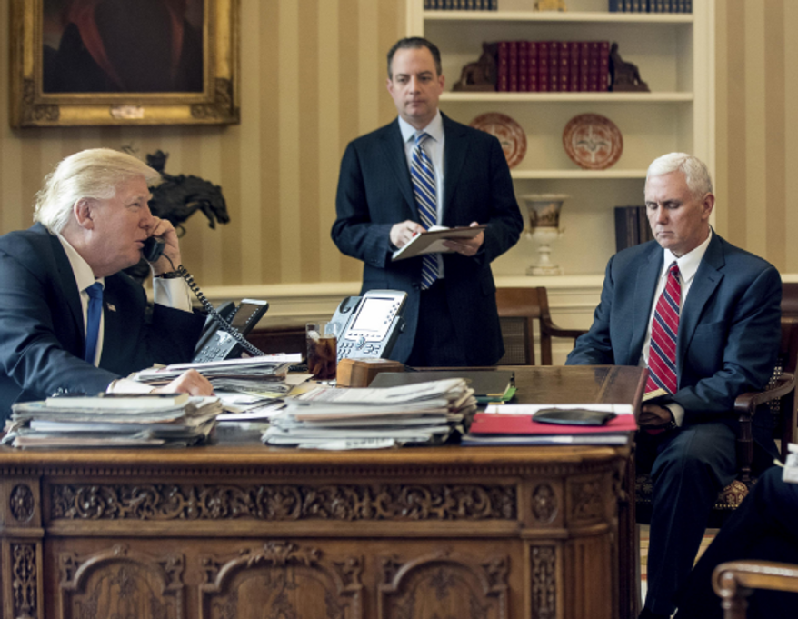 President Donald Trump talks on the phone in the Oval Office with Vice President Mike Pence and Chief of Staff Reince Priebus nearby. (Associated Press photo)