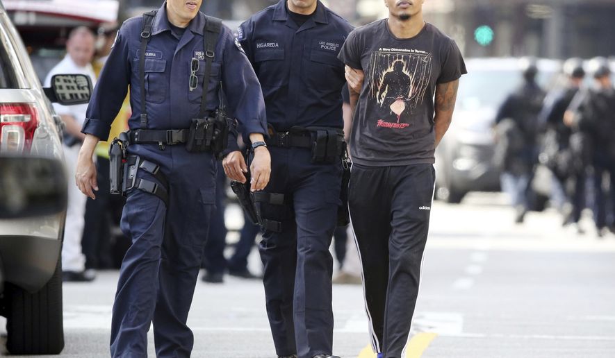 Los Angeles police officers take a man into custody after an hours-long search of a building in Los Angeles' downtown Garment District Monday, April 24, 2017. (AP Photo/Reed Saxon)