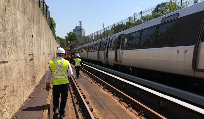 In this photo taken July 25, 2016, Metro general manager Paul Wiedefeld walks along a track that&#x27;s been closed for maintenance while an orange line train rolls along the other track in northern Virginia. (AP Photo/Ben Nuckols) **FILE**