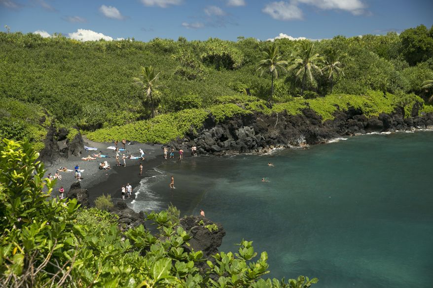 File - In this Sept. 24, 2014, file photo, beach goers frolic on the black sand beach at Waianapanapa State Park in Hana, Hawaii. A California couple on their honeymoon believe they contracted the rat lungworm disease in the remote Hana area of Maui early this year. After the newlyweds' plight with the disease recently got attention online, the couple and some experts accused Hawaii of failing to adequately warn tourists and residents of the danger. (AP Photo/Marco Garcia, File)
