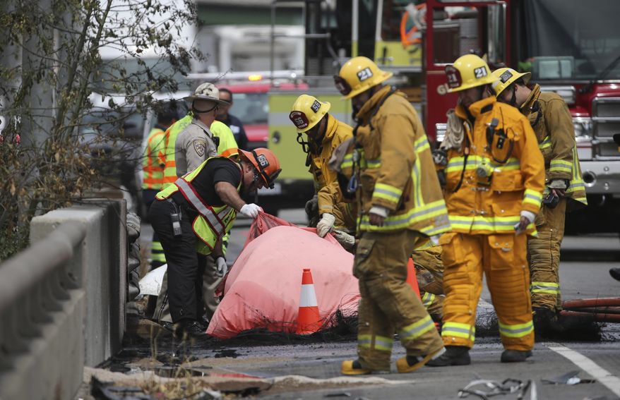 Investigators view a body amid the wreckage after a fiery collision of two big trucks and several smaller vehicles killed one person and injured several others while triggering a massive traffic jam on Interstate 5 just north of downtown Los Angeles Tuesday, April 25, 2017. (AP Photo/Reed Saxon)