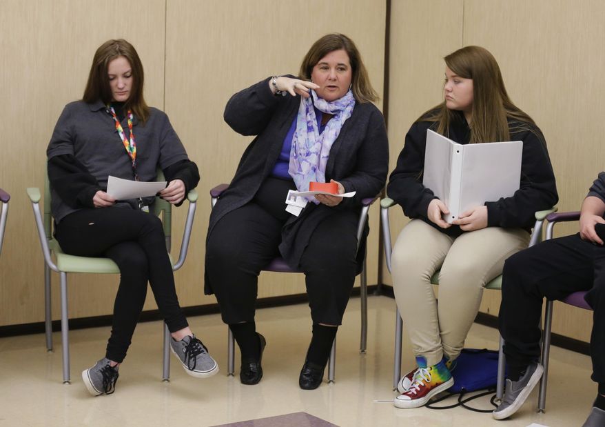 In this Monday, March 13, 2017 photo, Rachelle Gardner, center, chief operating officer of Hope Academy and student Logan Snyder, right, lead an all-school meeting called "circle" before the start of classes in Indianapolis. For teenagers in treatment for addiction, returning to school means resisting offers to get high with old friends. Researchers said these kids do better at special “recovery schools” that use peer pressure in a different way, to support sobriety. (AP Photo/Michael Conroy)