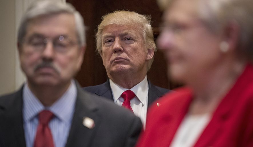President Donald Trump, flanked by Iowa Gov. Terry Branstad, left, and Alabama Gov. Kay Ivey,  attends a federalism event before signing the Education Federalism Executive Order, Wednesday, April 26, 2017, in the Roosevelt Room of the White House in Washington.  (AP Photo/Andrew Harnik)