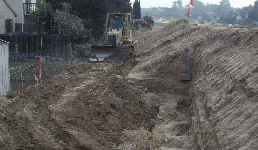 In this April 28, 1993 photo provided by the San Diego Natural History Museum, a bulldozer refills the Cerutti Mastodon site in San Diego, Calif., after the excavation and salvage of fossils. In a report released on Wednesday, April 26, 2017, researchers say the southern California site shows evidence of human-like behavior from about 130,000 years ago, when bones and teeth of an elephant-like mastodon were evidently smashed with rocks. (San Diego Natural History Museum via AP)
