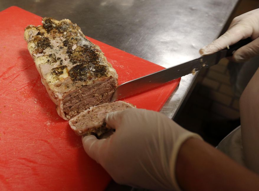 In this March 2, 2017 photo, chef's apprentice Stevie Gonzales slices hogs head cheese at the Palace Cafe in New Orleans. In a region that takes its food seriously, and has the James Beard awards to back it up, the meat passes muster with area chefs who praise its taste and have turned it into savory prosciutto, chorizo and meatballs. (AP Photo/Gerald Herbert)
