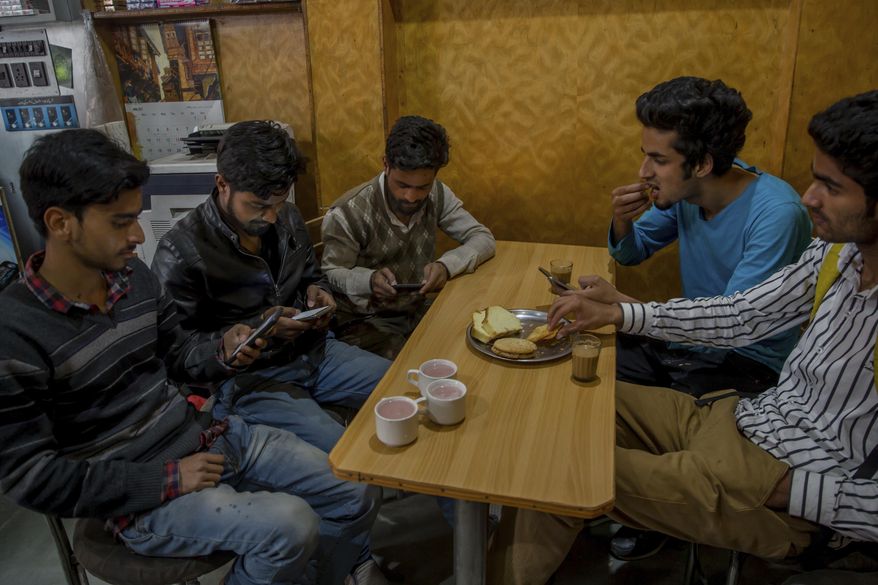 Kashmiri students browse internet on their mobile phones as they sits inside a restaurant in Srinagar, Indian controlled Kashmir, Wednesday, April 26, 2017. On Wednesday, authorities ordered internet service providers to block 16 social media sites, including Facebook and Twitter, and popular online chat applications for one month "in the interest of maintenance of public order." The government has often halted internet service in the region in the past in an attempt to prevent anti-India demonstrations from forming. But this is the first time authorities have shut down social media following the circulation of videos of alleged abuse by Indian soldiers.(AP Photo/Dar Yasin)