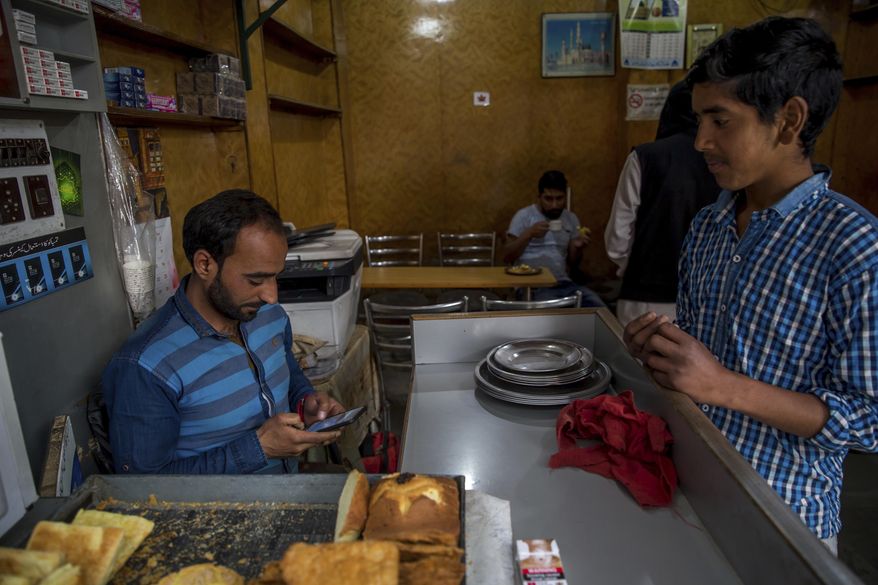 Kashmiri man Umar Rashid, browses internet on his mobile phone as he sits inside his restaurant in Srinagar, Indian controlled Kashmir, Wednesday, April 26, 2017. On Wednesday, authorities ordered internet service providers to block 16 social media sites, including Facebook and Twitter, and popular online chat applications for one month "in the interest of maintenance of public order." The government has often halted internet service in the region in the past in an attempt to prevent anti-India demonstrations from forming. But this is the first time authorities have shut down social media following the circulation of videos of alleged abuse by Indian soldiers. (AP Photo/Dar Yasin)
