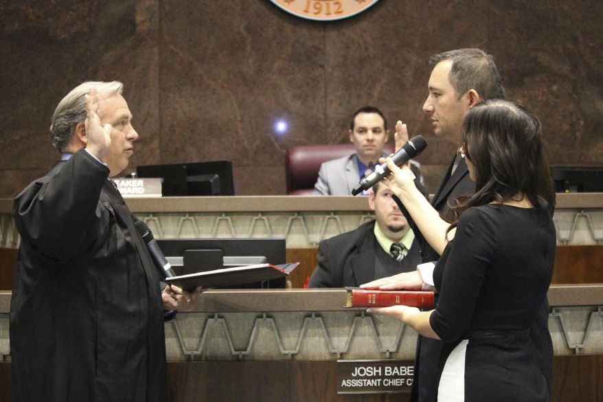Maricopa County Superior Court Judge Adam Driggs, left, swears in Peoria real estate broker and former city councilman, Republican Ben Toma as a member of the Arizona House of Representatives in Phoenix, Ariz., on Wednesday, April 26, 2017. His wife, Ana Toma, right, holds the Bible. Toma was picked from three nominees by the county Board of Supervisors to replace Republican Peoria Rep. Phil Lovas, who resigned to take a job with the Trump Administration. (AP Photo/Bob Christie)