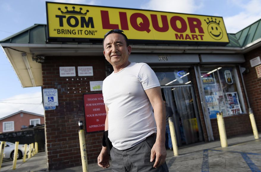 James Oh, owner of Tom's Liquors, poses outside his store at the intersection of Florence and Normandie, Tuesday, April 18, 2017, in Los Angeles. Most of those groceries weren't there when he took the place over, Oh says, so he moved out some of the booze to make room (although there's still plenty available) and brought in necessities like milk, eggs, sugar and an array of spices and sauces favored by Latino and African-American customers. (AP Photo/Chris Pizzello)