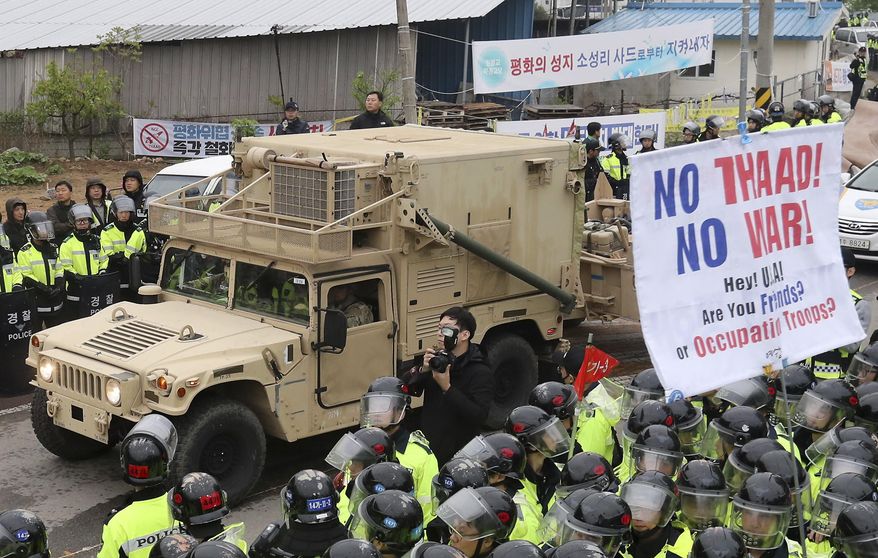U.S. military vehicle moves past banners opposing a plan to deploy an advanced U.S. missile defense system called Terminal High-Altitude Area Defense, or THAAD, as South Korean police officers stand guard in Seongju, South Korea, Wednesday, April 26, 2017. South Korea says key parts of a contentious U.S. missile defense system have been installed a day after rival North Korea showed off its military power. (Kim Jun-hum/Yonhap via AP)