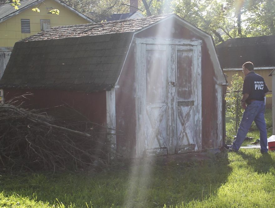 In this photo provided by the Blanchester Police Department, an officer walks near a shed owned by Dennis Dunn, who was arrested Wednesday, April 26, 2017, on a charge of kidnapping in Blanchester, Ohio. A woman’s cries for help from Dunn's shed led to her rescue from a pit in the shed, where police in Ohio said she was being held captive. (Blanchester Police Department via AP)
