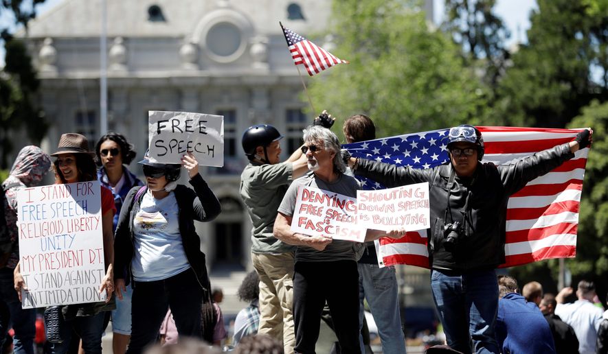Demonstrators hold signs and flags Thursday, April 27, 2017, in Berkeley, Calif. Demonstrators gathered near the University of California, Berkeley campus amid a strong police presence and rallied to show support for free speech and condemn the views of Ann Coulter and her supporters. (AP Photo/Marcio Jose Sanchez)
