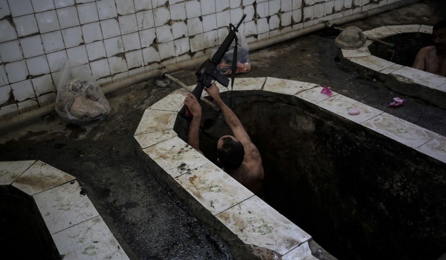 A federal police officer puts his machine gun on the edge of the bath in the Hamam Alil spa, south of Mosul, Iraq, Thursday April, 27, 2017. The spa reopened several months ago after the town was liberate from the Islamic State group. Many Iraqi soldiers visit the spa, located half an hour south of Mosul, in between fighting against the Islamic State group for relaxation. (AP Photo/Bram Janssen)