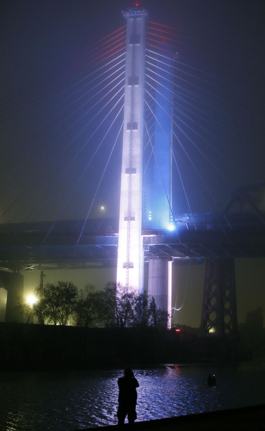 A photographer pauses to take pictures during the grand opening of the new Kosciuszko Bridge span connecting Brooklyn and Queens after a performance of the "New York Harbor of Lights" at the bridge's grand opening ceremony on a foggy and misty night, Thursday, April 27, 2017, in New York. Sections of the old Kosciuszko Bridge are scheduled to be demolished this summer. (AP Photo/Kathy Willens)