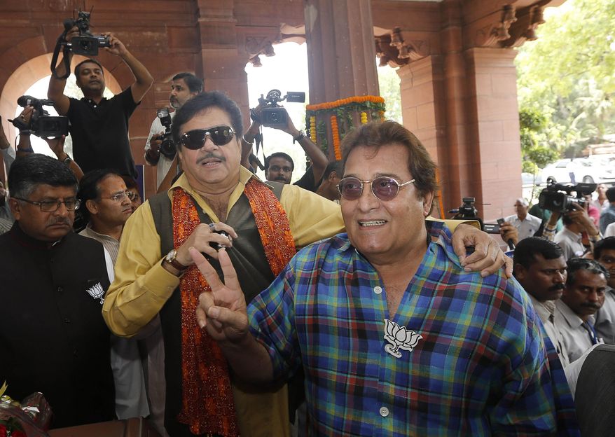 FILE - In this May 20, 2014, file photo, former Indian politician and Bollywood actor Vinod Khanna, right, and Indian film actor turned politician Shatrughan Sinha pose for cameras as they arrive for the BJP parliamentary party meeting in New Delhi, India. A hospital official says Vinod Khanna, a dashing Bollywood actor turned politician, has died of cancer in Mumbai. He was 70. (AP Photo/Saurabh Das, File)