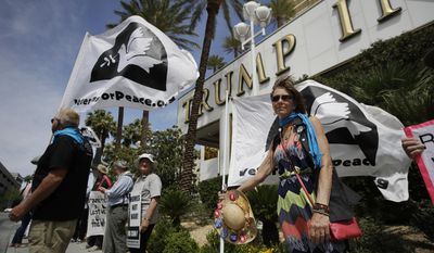 Laurie Tanner, right, holds up a flag during a protest against drone warfare outside of the Trump International hotel Thursday, April 27, 2017, in Las Vegas. The protest was held a day after a man was accused of trying to set fire to the property. The incidents are just the latest targeting the president&#x27;s gold glass tower just off the Las Vegas Strip. (AP Photo/John Locher)