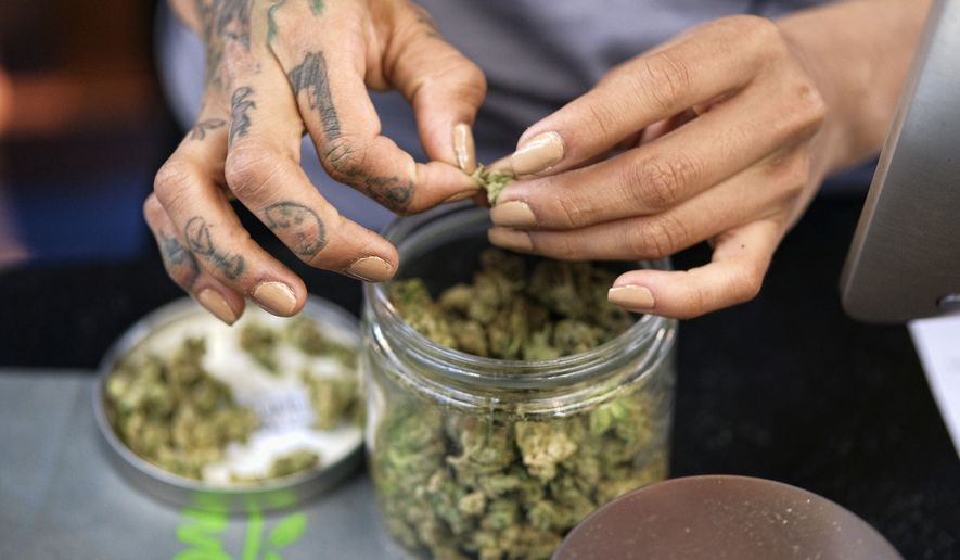 In this April 15, 2017, file photo a budtender weighs out marijuana for a customers at ShowGrow, a medical marijuana dispensary in downtown Los Angeles. (AP Photo/Richard Vogel, File)