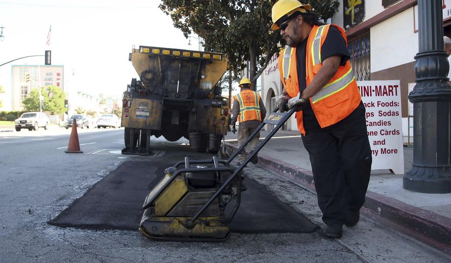 ADDS LOCAL PROJECTS COULD START SOONER - FILE - In this Sept. 11, 2014 file photo, city worker Ralph Mendoza repairs a street in downtown Los Angeles. California drivers will see their gas prices rise in November 2017 and will pay more to register their vehicles come January. The California Transportation Commission prioritize projects for the funding and the first construction work will likely begin in the summer of 2018, said Mark Dinger, a spokesman for Caltrans. However, local projects could get off the ground sooner, said Randy Breault, a public works director in Brisbane who serves on the board of directors for the California League of Cities. (AP Photo/Nick Ut, File)