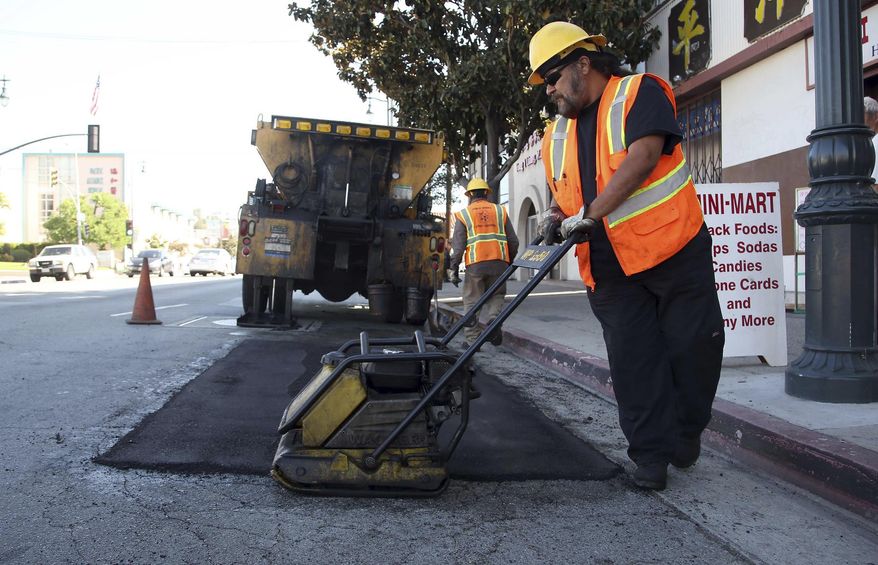 ADDS LOCAL PROJECTS COULD START SOONER - FILE - In this Sept. 11, 2014 file photo, city worker Ralph Mendoza repairs a street in downtown Los Angeles. California drivers will see their gas prices rise in November 2017 and will pay more to register their vehicles come January. The California Transportation Commission prioritize projects for the funding and the first construction work will likely begin in the summer of 2018, said Mark Dinger, a spokesman for Caltrans. However, local projects could get off the ground sooner, said Randy Breault, a public works director in Brisbane who serves on the board of directors for the California League of Cities. (AP Photo/Nick Ut, File)