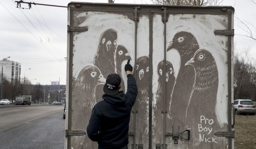 In this photo taken on Saturday, April 22, 2017, artist Nikita Golubev draws pigeons on the back of a dirty delivery truck, in Moscow, Russia. The grimy trucks traversing the polluted and dusty streets of Moscow have inspired Golubev to use white vans and trucks as his canvas to create this ephemeral street art and signs his drawings Pro Boy Nick. (AP Photo/Pavel Golovkin)