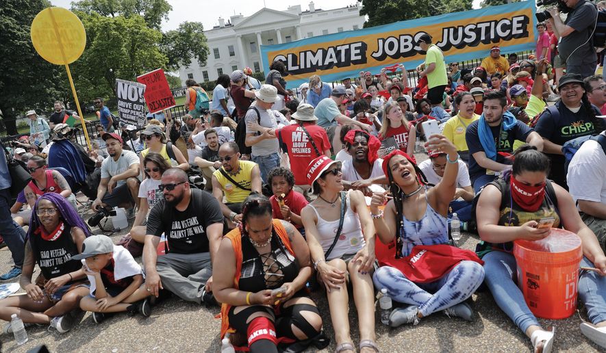 Demonstrators sit on the ground along Pennsylvania Ave. in front of the White House in Washington, Saturday, April 29, 2017, during a demonstration and march. Thousands of people gathered across the country to march in protest of President Donald Trump&#x27;s environmental policies, which have included rolling back restrictions on mining, oil drilling and greenhouse gas emissions at coal-fired power plants. The demonstrators sat down for 100 seconds to mark President Trump&#x27;s first 100 days in office. (AP Photo/Pablo Martinez Monsivais)