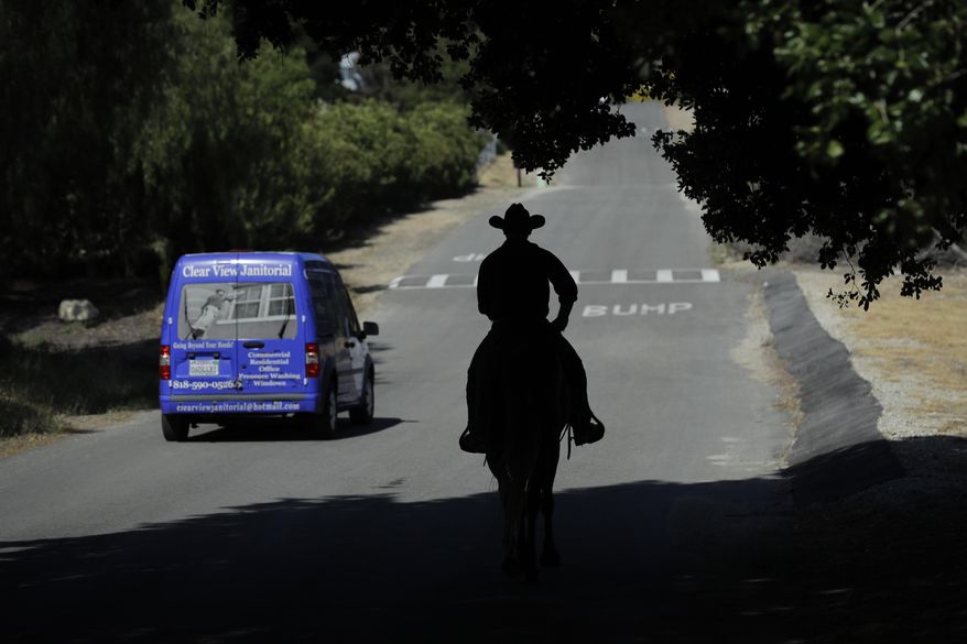 In this Wednesday, April 19, 2017 photo, Iraq war veteran Colt Romberger rides his horse, Gus, along the road in Santa Clarita, Calif. Romberger is training his horse for a ride from California to the Vietnam War Memorial in Washington in hopes to raise money for veterans causes and tell the public about the devastating effects Agent Orange has had on the bodies of now-aging veterans of the Vietnam War. His father, a Vietnam War veteran, died of a brain disease associated with Agent Orange. (AP Photo/Jae C. Hong)