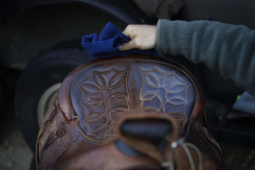 In this Wednesday, April 19, 2017 photo, Iraq war veteran Colt Romberger maintains a saddle before taking his horse for a morning workout in Santa Clarita, Calif. Romberger is training his horse for a ride from California to the Vietnam War Memorial in Washington in hopes to raise money for veterans causes and tell the public about the devastating effects Agent Orange has had on the bodies of now-aging veterans of the Vietnam War. His father, a Vietnam War veteran, died of a brain disease associated with Agent Orange. (AP Photo/Jae C. Hong)