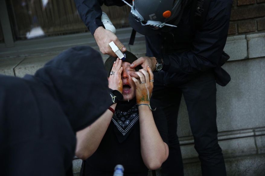 FILE - In this Sunday, May 1, 2016, file photo, a person reacts after being pepper sprayed during an anti-capitalism protest in Seattle. Tens of thousands of immigrants and their supporters are expected to rally Monday, May 1, 2017, against Trump administration policies. While immigration reform has been a key focus of May 1 demonstrations in the U.S. for over a decade, the roots of May Day, or International Workers Day, stretch back over a century. (Grant Hindsley/seattlepi.com via AP, File)