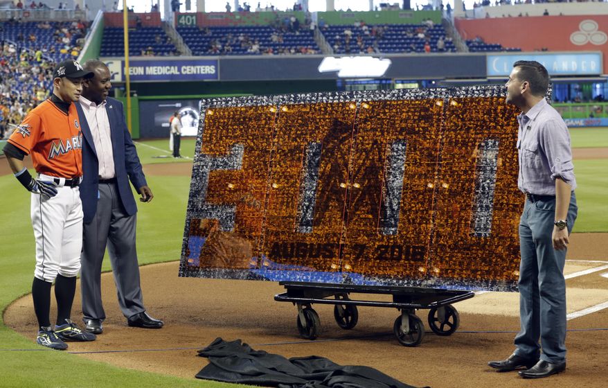 Miami Marlins' Ichiro Suzuki, left, stands with Michael Hill, president of baseball operations, center, and president David Samson, right, for a pregame ceremony honoring Ichiro's 3,000th career hit before a baseball game against the Pittsburgh Pirates, Sunday, April 30, 2017, in Miami. (AP Photo/Lynne Sladky)