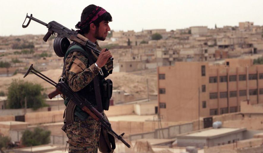 This Sunday, April 30, 2017 photo provided by the Syria Democratic Forces (SDF), shows a fighter from the SDF carrying weapons as he looks toward the northern town of Tabqa, Syria. U.S.-backed opposition fighters led by Syrian Kurdish forces captured more territory from the Islamic State group in the northern town of Tabqa on Monday, pushing the extremists to northern neighborhoods, close to one of Syria&#39;s largest dams. (Syrian Democratic Forces, via AP)