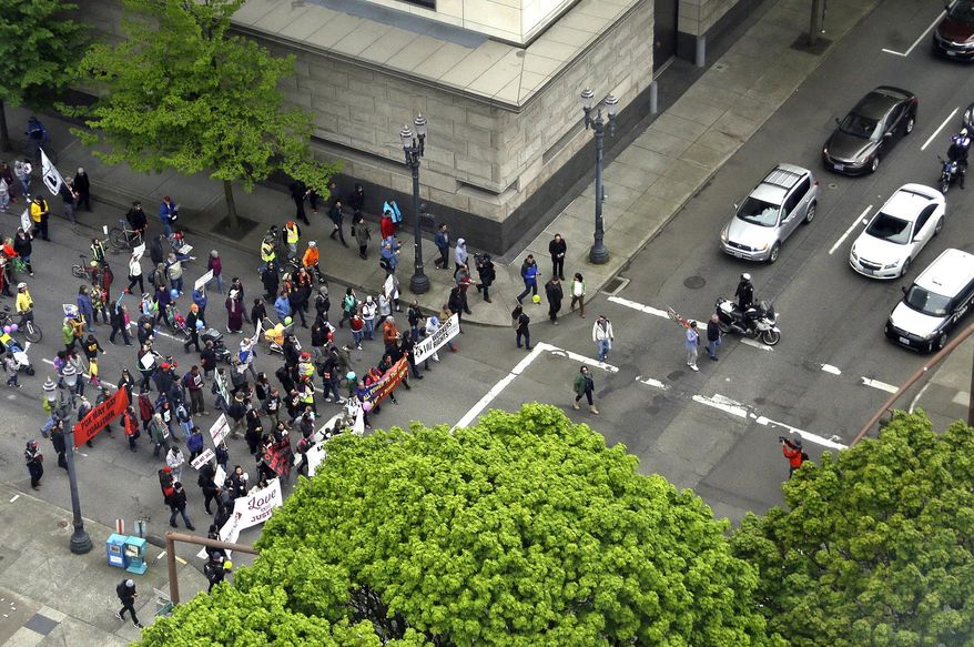 Protesters march through the street as police hold back traffic in Portland, Ore., Monday, May 1, 2017. Immigrant and union groups will march in cities across the United States to mark May Day and protest against President Donald Trump's efforts to boost deportations. (AP Photo/Don Ryan)