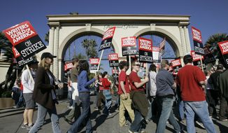In this Dec. 13, 2007, file photo, striking writers walk the picket line outside Paramount Studios in Los Angeles. (AP Photo/Nick Ut, File)