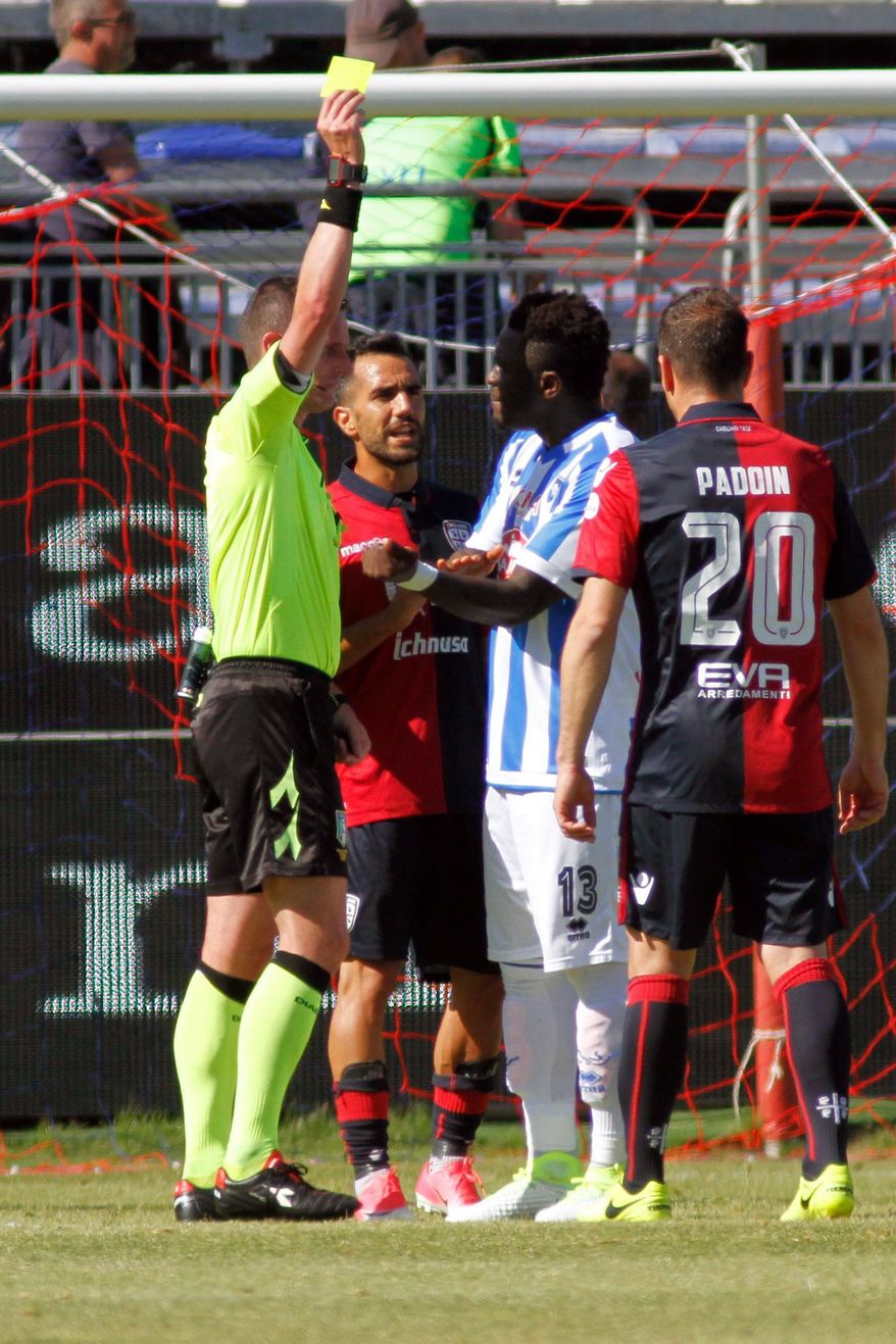 Referee Daniele Minelli shows the yellow card to Pescara's Sulley Muntari, second from right, during a Serie A soccer match between Pescara and Cagliari, at the Cagliari Sant'Elia stadium, Italy, Sunday, April 30, 2017. Pescara midfielder Sulley Muntari walked off the pitch in protest during his side's Serie A match at Cagliari after being booked for complaining to the referee about racist abuse from fans. Muntari told referee Daniele Minelli about the racist chants from home fans in the final minute of Pescara's 1-0 defeat but the official showed the Ghana midfielder a yellow card. (Fabio Murru/ANSA via AP)