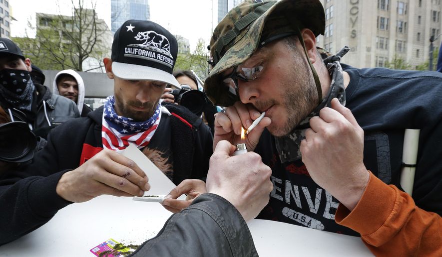 Mark Burrell, right, and a man who said he goes by the name Abundis, left, light marijuana joints Monday, May 1, 2017, during a May Day protest in Seattle. The two men identify with constitutionalist and libertarian ideals and had been arguing with counter protesters when they decided to smoke pot together with their opponents. (AP Photo/Ted S. Warren) **FILE**
