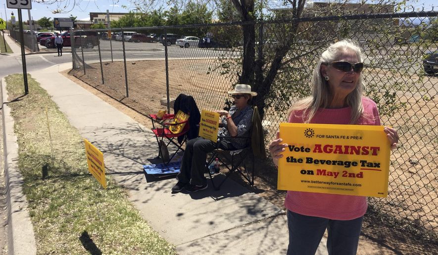 Coca-Cola Bottling Co. of Santa Fe Vice President Kathy Hart, 65, right, urges voters to reject a tax on sugary beverages outside a polling center in Santa Fe, N.M., on Tuesday, May 2, 2017. Voters in New Mexico's capital city were deciding whether to add a tax on sugary sodas and other sweetened beverages that would follow the examples of several cities across the country. The proposed tax in Santa Fe would pay to expand early childhood education. (AP Photo/Morgan Lee)