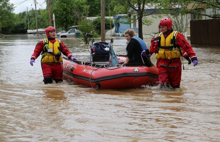 Members of the High Ridge fire department take a woman out of her trailer at the Village Green Estates trailer park on Monday, May 1, 2017, in Cedar Hill, Mo. Torrential rains over the weekend caused flash flooding across Missouri, and as storm drains and fields continue to pour into rivers, they continue to rise. (J.B. Forbes/St. Louis Post-Dispatch via AP)