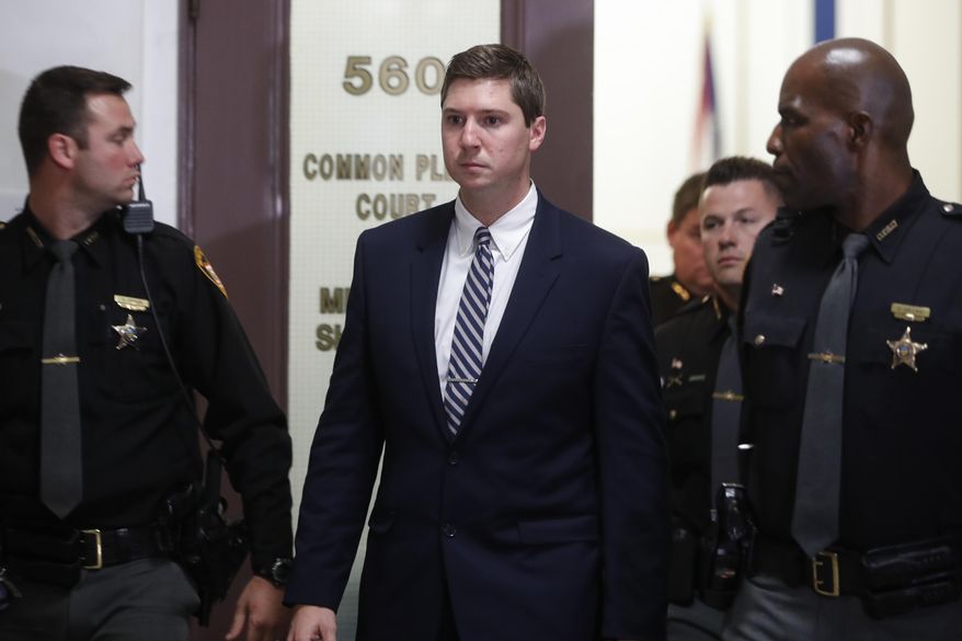 FILE – In this Nov. 11, 2016, file photo, former University of Cincinnati police officer Ray Tensing, center, leaves court during jury deliberations in his murder trial in Cincinnati. Attorneys for Tensing, charged with killing an unarmed black man, filed a motion Monday, May 1, 2017, saying jurors at Tensing's retrial shouldn't see the T-shirt with a Confederate flag emblem he was wearing under his uniform, The Cincinnati Enquirer reports. A jury deadlocked and a judge declared a mistrial Nov. 12, 2016, on charges of murder and voluntary manslaughter in the July 2015 shooting of unarmed black motorist Sam DuBose during a traffic stop. A photo of the T-shirt was shown at Tensing's first trial. (AP Photo/John Minchillo, File)