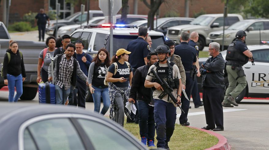 An officer leads a group of students walking out of the building as Irving police officers work at a fatal shooting scene on the North Lake College campus in Irving, Texas, Wednesday, May 3, 2017. The situation prompted a lockdown at the school in the Dallas suburb. (Jae S. Lee/The Dallas Morning News via AP)