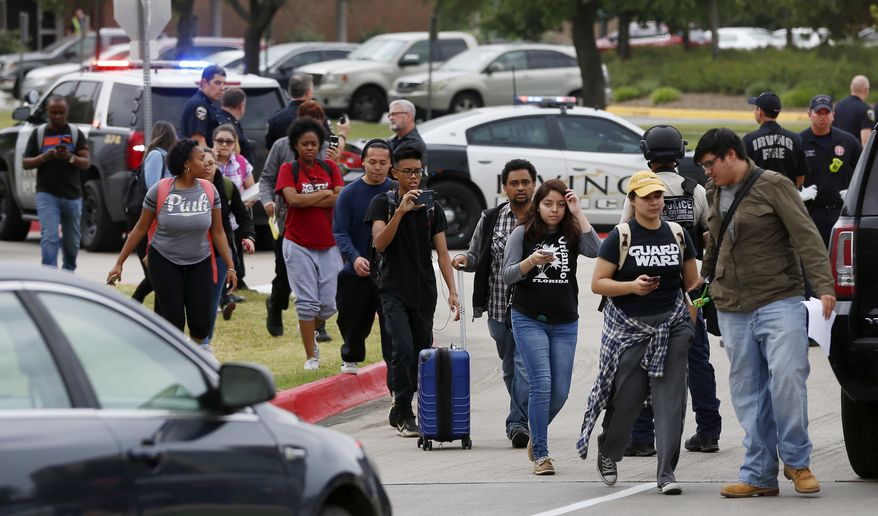 Students walk out of the building as Irving police officers work at the shooting scene on the North Lake College campus in Irving, Texas, Wednesday, May 3, 2017. The situation prompted a lockdown at the school in the Dallas suburb. (Jae S. Lee/The Dallas Morning News via AP)