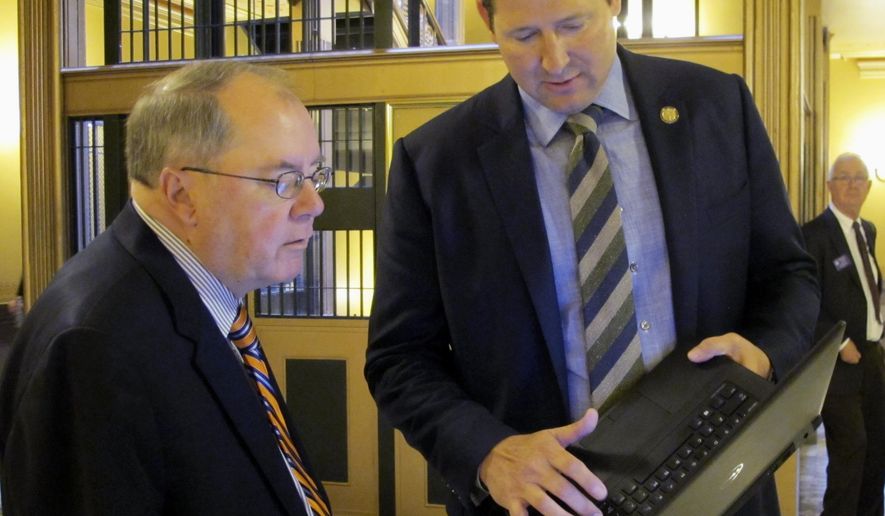 Kansas Senate Minority Leader Anthony Hensley, left, D-Topeka, confers with House Speaker Ron Ryckman Jr., right, R-Olathe, outside the Senate chamber, Wednesday, May 3, 2017, at the Statehouse in Topeka, Kan. Ryckman is showing Hensley figures related to a proposal for increasing income taxes to fix the state budget, trying to persuade Hensley that it also raises enough new revenue to boost aid to public schools. (AP Photo/John Hanna)